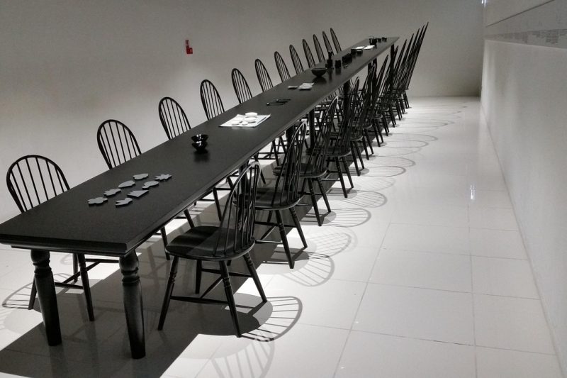 一间小型会议室里，三位编辑围坐在长桌旁核对课件格式对照表，白板上贴着彩色便签，窗外是阴天的城市天际线
